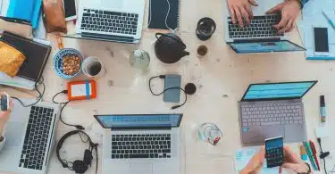 people sitting down near table with assorted laptop computers